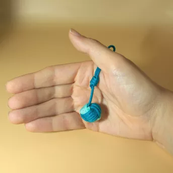 Porte-clés nœud touline bleu clair et vert océan tenu dans une main, détail des finitions artisanales en paracorde